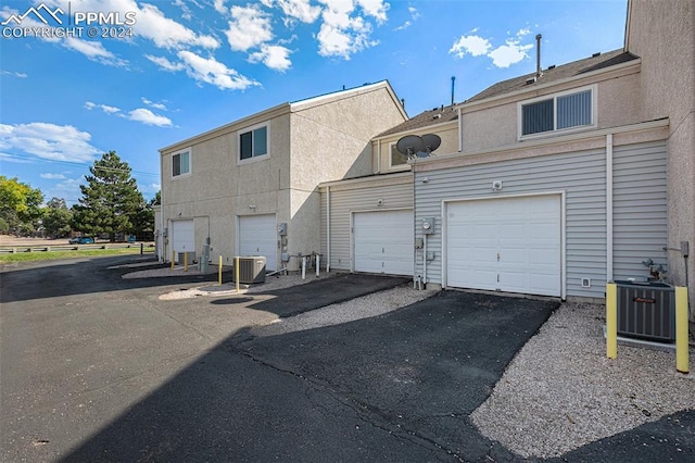 back of property with central AC unit and a garage