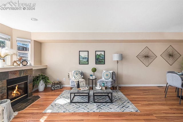 living area featuring a tiled fireplace and light hardwood / wood-style floors