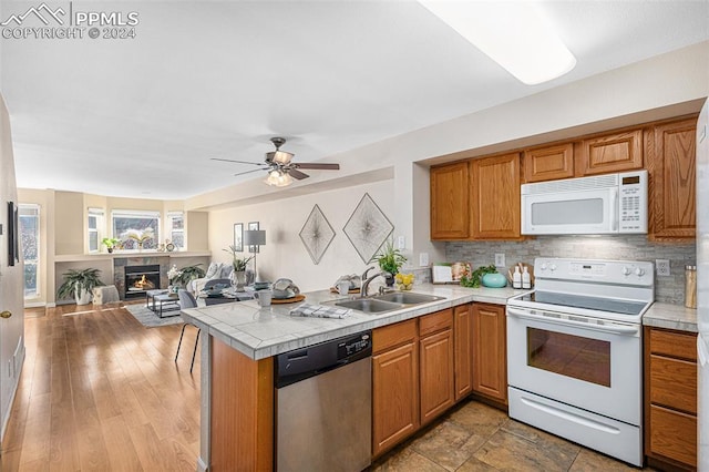 kitchen featuring white appliances, kitchen peninsula, light wood-type flooring, ceiling fan, and sink