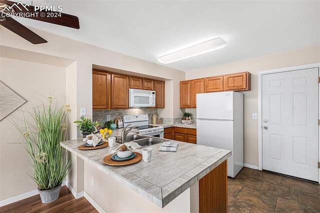 kitchen with tile counters, white appliances, backsplash, and kitchen peninsula