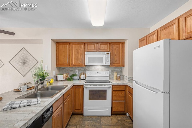 kitchen featuring backsplash, white appliances, sink, and tile countertops