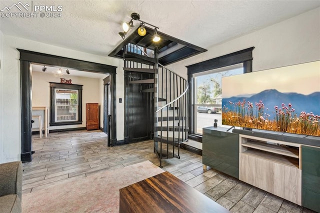 living room with a textured ceiling, light wood-type flooring, and rail lighting