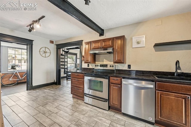 kitchen with a textured ceiling, sink, stainless steel appliances, and a wealth of natural light