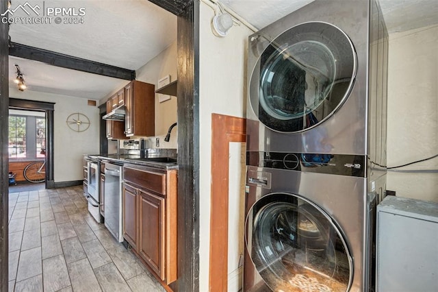 clothes washing area featuring light wood-type flooring, sink, and stacked washer and clothes dryer