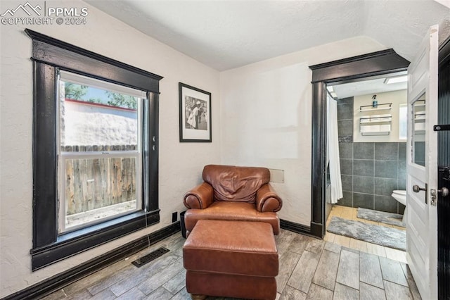 sitting room featuring light wood-type flooring and tile walls