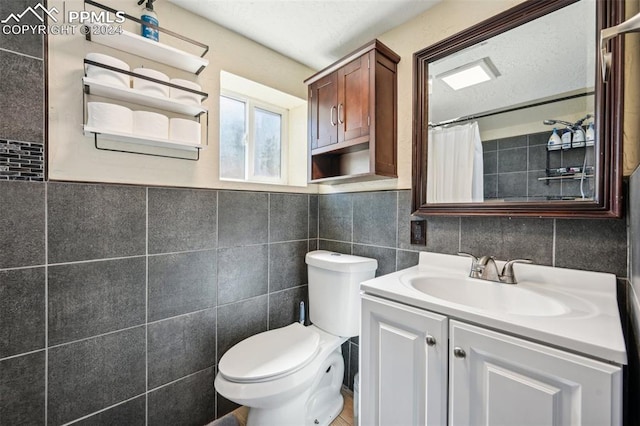 bathroom with tile walls, curtained shower, vanity, a textured ceiling, and toilet