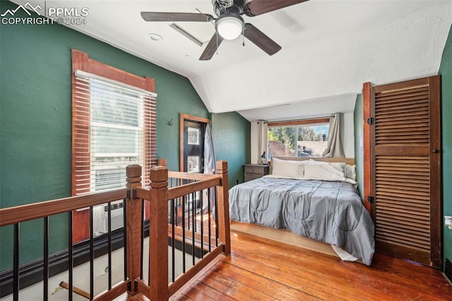 bedroom featuring ceiling fan, hardwood / wood-style flooring, vaulted ceiling, and multiple windows