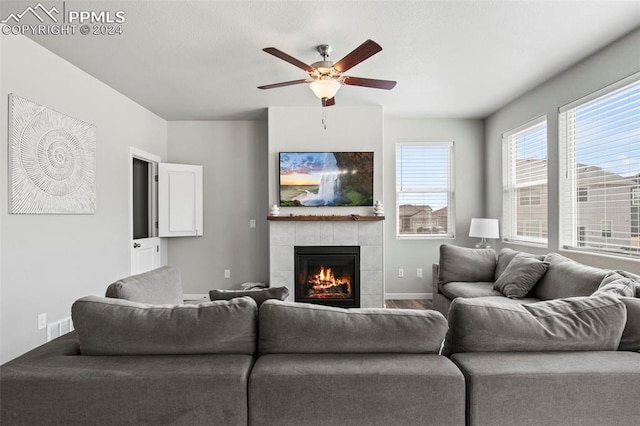 living room featuring a tiled fireplace and ceiling fan