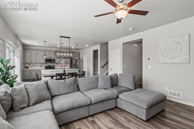 living room with wood-type flooring and ceiling fan with notable chandelier