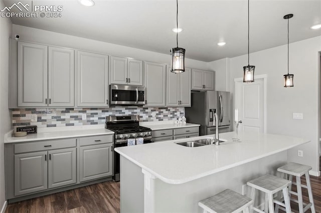 kitchen with gray cabinets, stainless steel appliances, dark hardwood / wood-style floors, and tasteful backsplash