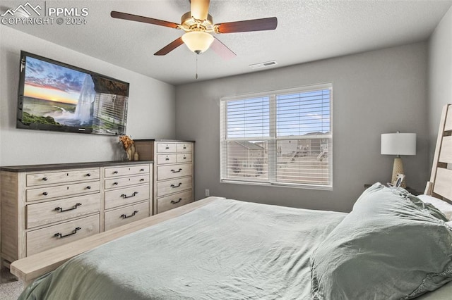 bedroom with ceiling fan and a textured ceiling