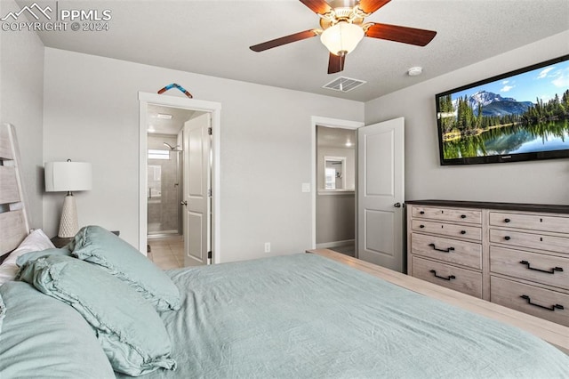 tiled bedroom featuring connected bathroom, ceiling fan, and a textured ceiling