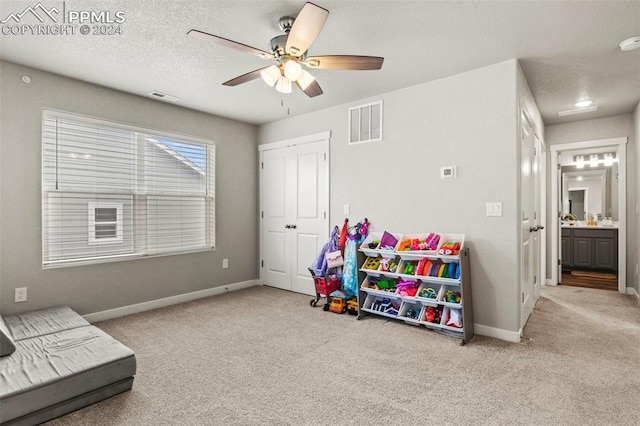 game room featuring a textured ceiling, ceiling fan, and light carpet