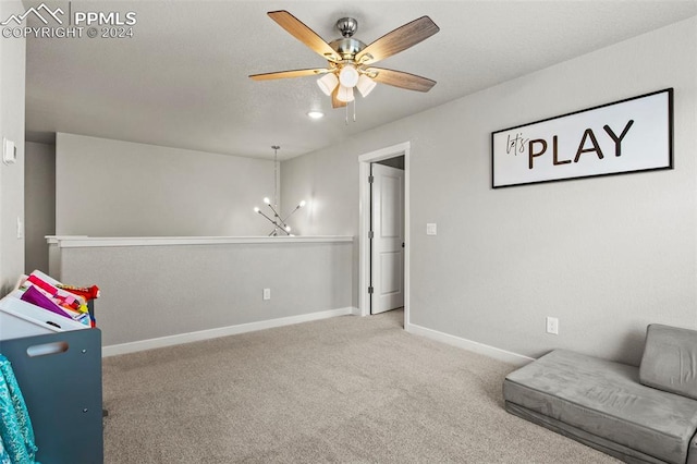 living area featuring ceiling fan with notable chandelier and carpet flooring