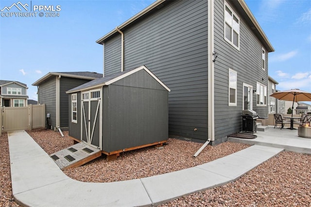 view of side of property with a patio and a storage unit