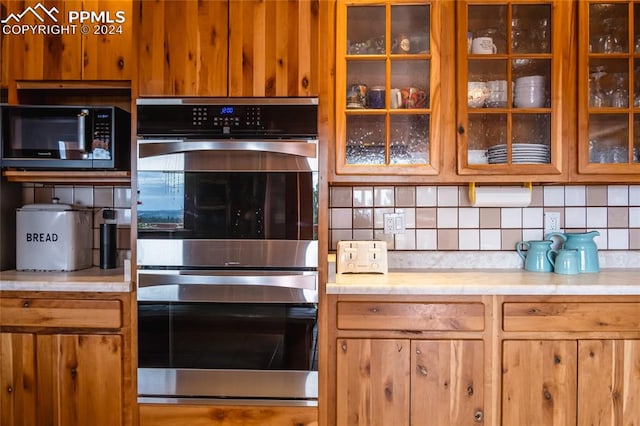 kitchen with stainless steel double oven and decorative backsplash