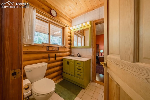 bathroom with a wealth of natural light, rustic walls, vanity, and toilet