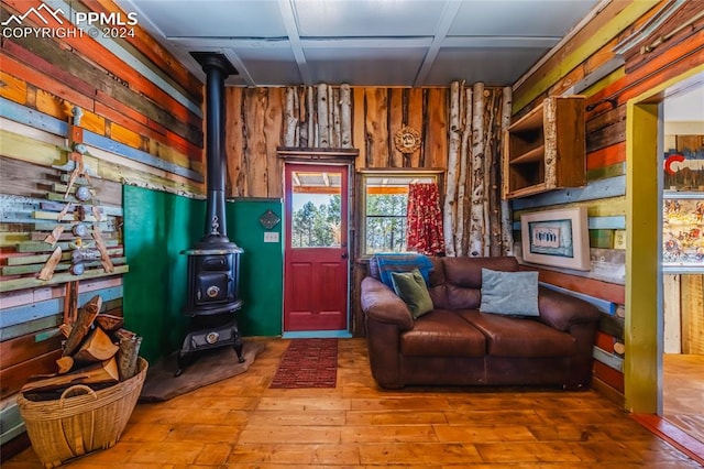 living room with coffered ceiling, wood walls, hardwood / wood-style floors, and a wood stove