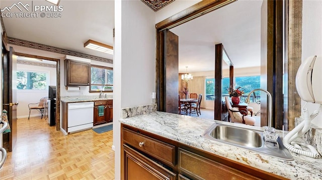 kitchen with white dishwasher, light parquet floors, decorative light fixtures, sink, and a notable chandelier