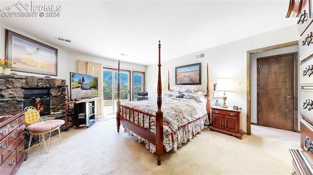 bedroom with light carpet and a fireplace