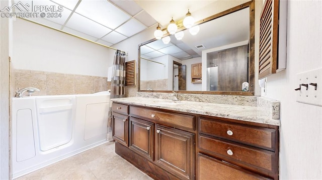 bathroom featuring vanity, independent shower and bath, a drop ceiling, tile patterned floors, and tile walls