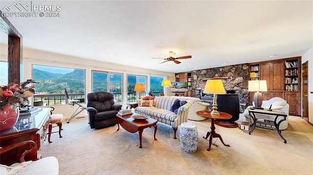 carpeted living room with ceiling fan, a mountain view, and a fireplace