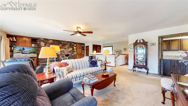 living room featuring ceiling fan, a stone fireplace, and light carpet