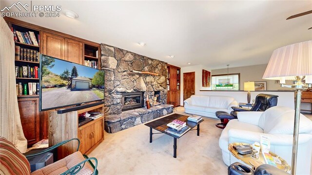 carpeted living room with ceiling fan and a fireplace