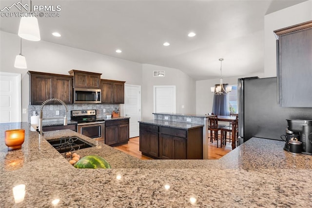 kitchen featuring dark brown cabinets, decorative light fixtures, stainless steel appliances, an inviting chandelier, and vaulted ceiling