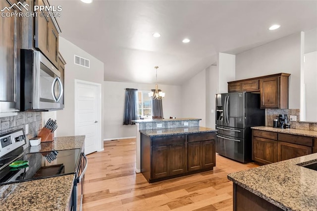 kitchen featuring appliances with stainless steel finishes, lofted ceiling, light hardwood / wood-style floors, and a chandelier