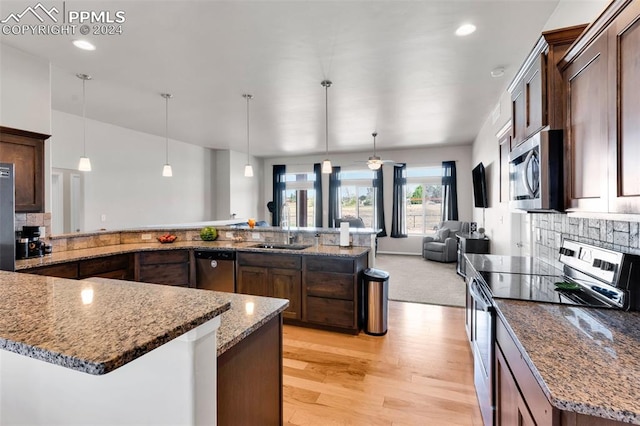 kitchen with a stone fireplace, sink, pendant lighting, and stainless steel appliances