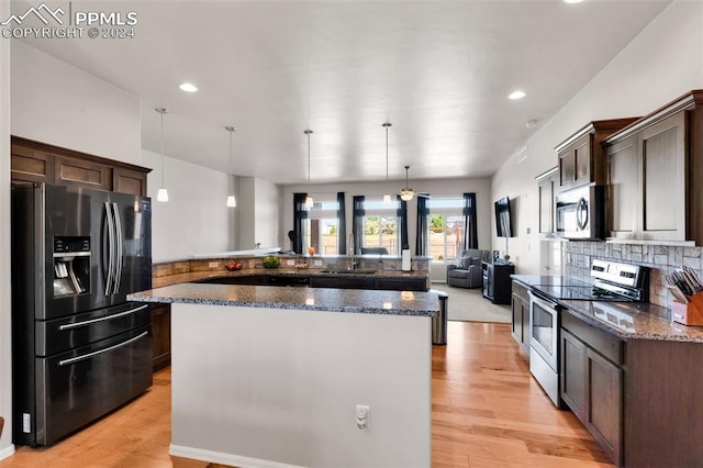 kitchen featuring dark brown cabinetry, pendant lighting, stainless steel appliances, and light wood-type flooring