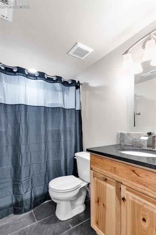 bathroom with walk in shower, vanity, toilet, and tile patterned floors