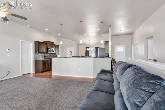 living room with vaulted ceiling, sink, ceiling fan with notable chandelier, and carpet flooring