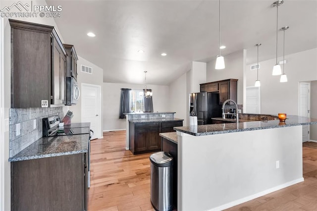 kitchen featuring appliances with stainless steel finishes, a center island with sink, and lofted ceiling