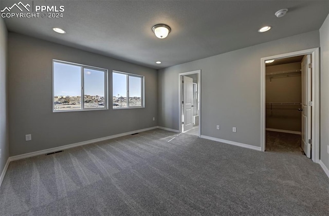 unfurnished bedroom featuring a closet, carpet, and a walk in closet