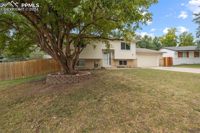 raised ranch featuring a front yard and a garage