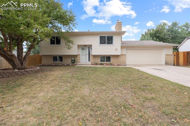 bi-level home featuring a garage and a front lawn