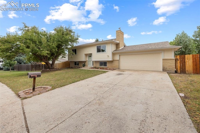 raised ranch featuring a garage and a front lawn