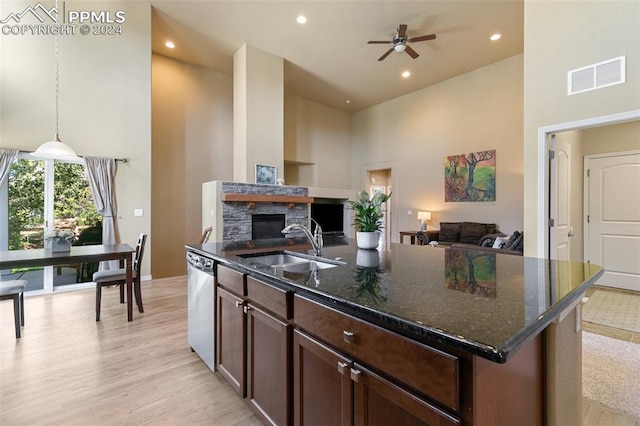 kitchen featuring pendant lighting, dishwasher, sink, an island with sink, and a high ceiling