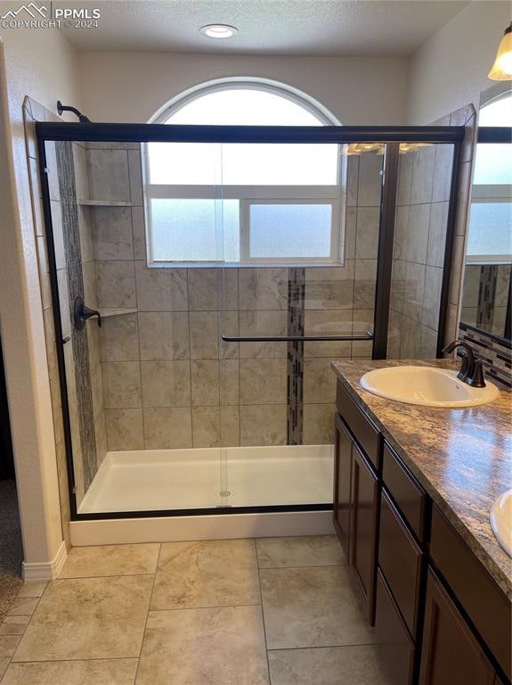 bathroom featuring walk in shower, tile patterned flooring, vanity, and a wealth of natural light