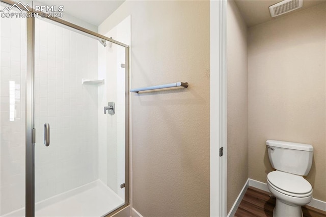 bathroom featuring hardwood / wood-style floors, toilet, and a shower with door