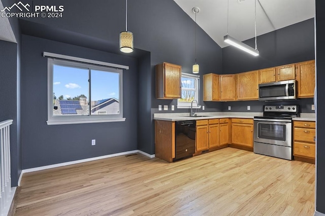 kitchen with hanging light fixtures, sink, high vaulted ceiling, appliances with stainless steel finishes, and light hardwood / wood-style floors