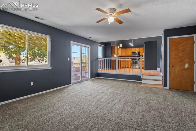 unfurnished living room with ceiling fan, carpet flooring, and a textured ceiling