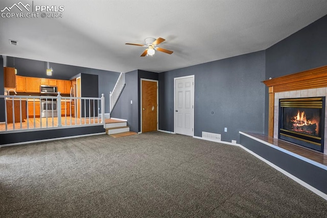 unfurnished living room with carpet, a fireplace, and ceiling fan