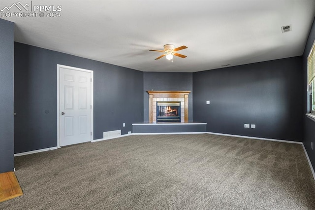 unfurnished living room featuring ceiling fan, a tiled fireplace, and carpet flooring