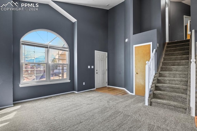 carpeted foyer featuring plenty of natural light and high vaulted ceiling