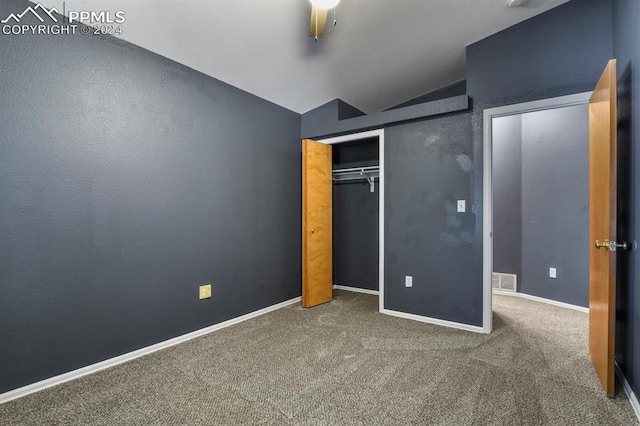 unfurnished bedroom with vaulted ceiling, a closet, and carpet floors