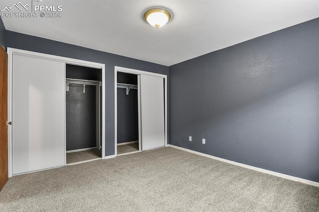 unfurnished bedroom with carpet floors and multiple closets