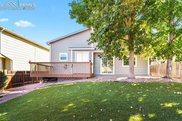 back of house featuring a wooden deck and a yard